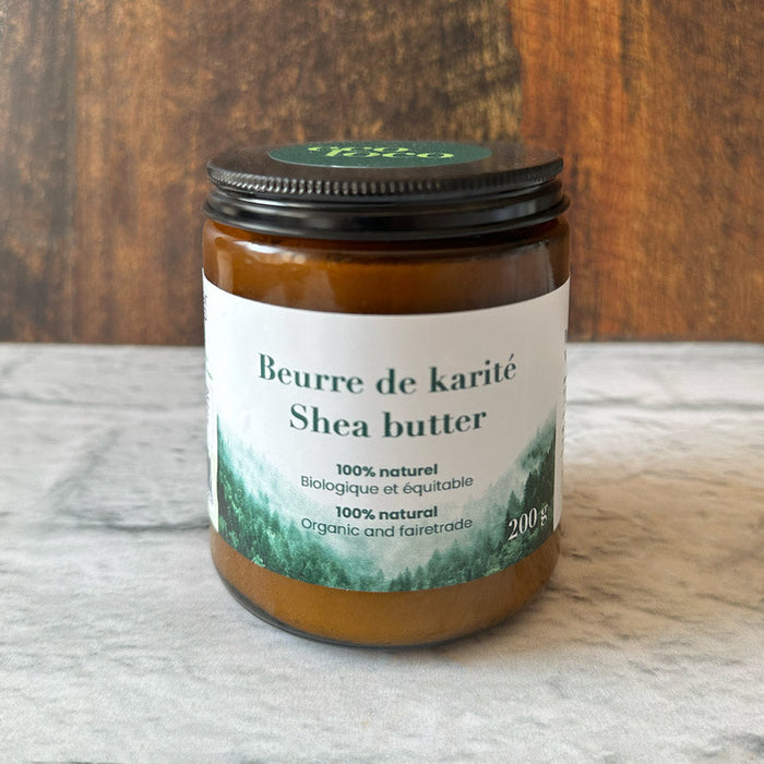 Pot de beurre de karité dans une main sur fond de bois