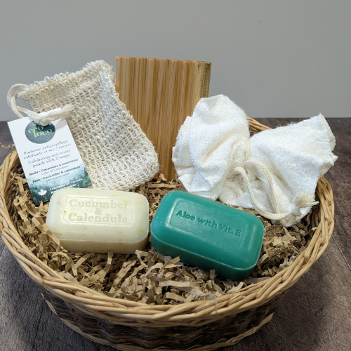 Ensemble d'un porte savon en cèdre du Québec, d'une fleur de douche sans plastique, d'une pochette à savon et de deux savons présentés dans un panier. 