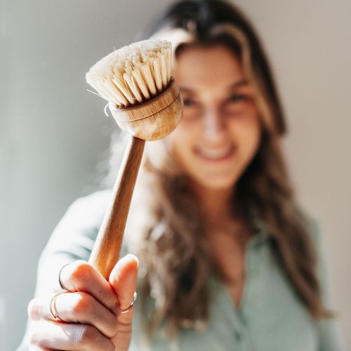 femme qui tient une brosse en bois devant son visage avec le fond flou