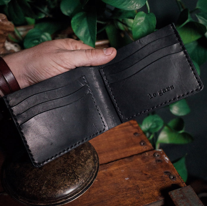 Compact black leather wallet with cash pocket and card slots
