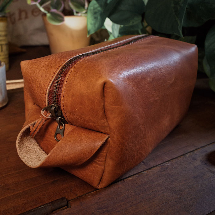 Compact cognac leather grooming bag with custom engraving
