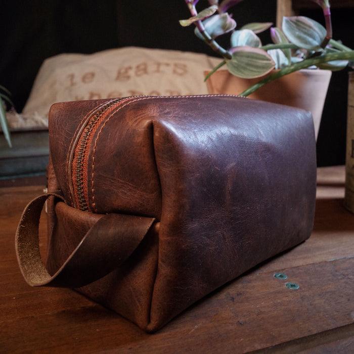 Minimalist dark-brown leather grooming bag with secure zipper closure
