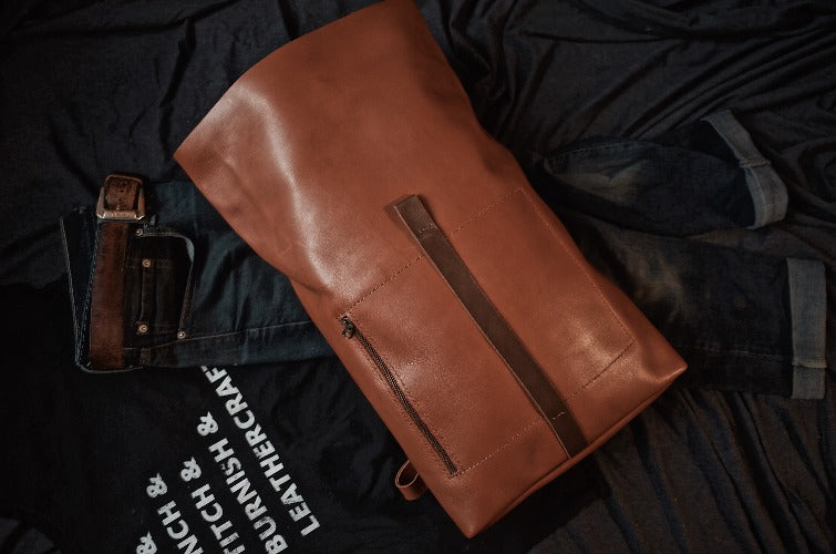 Handcrafted English tan leather roll-top backpack with spacious interior
