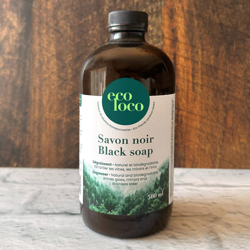Bouteille de savon noir black soap sur un comptoir blanc et un fond en bois