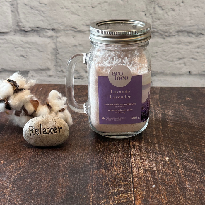 Un sel de bain à la lavande dans un pot Mason avec poignée et une roche avec l'écriture relaxer