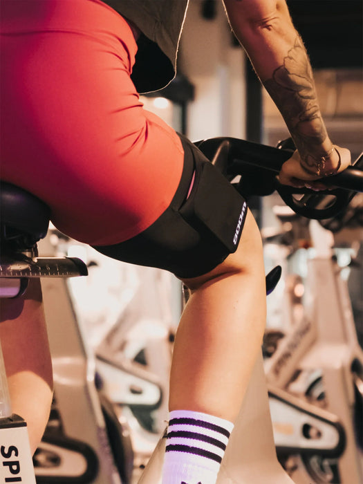 A picture of a woman on a stationnary bike wearing the legband sold by 800m.