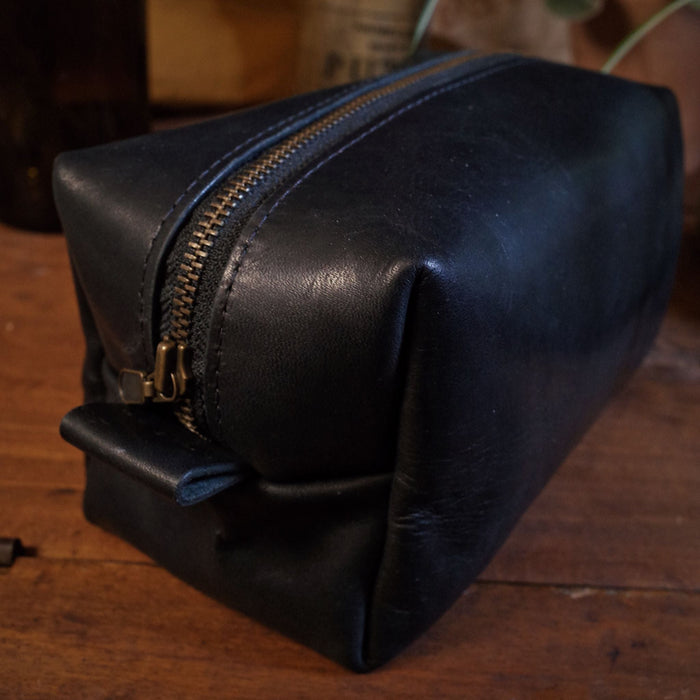 Full-grain black leather travel bag with reinforced zipper for security
