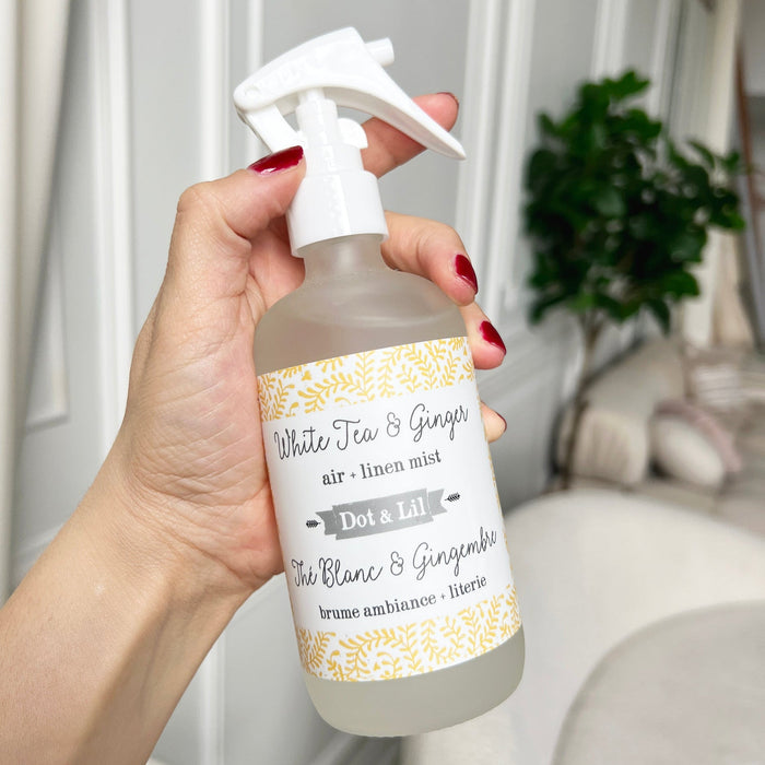 Hand holding a bottle of 'White Tea & Ginger' air linen mist with a decorative label.