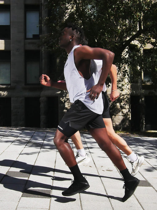 A full body picture of two people running in an urban area. One can clearly be seen wearing the legband sold by 800m.